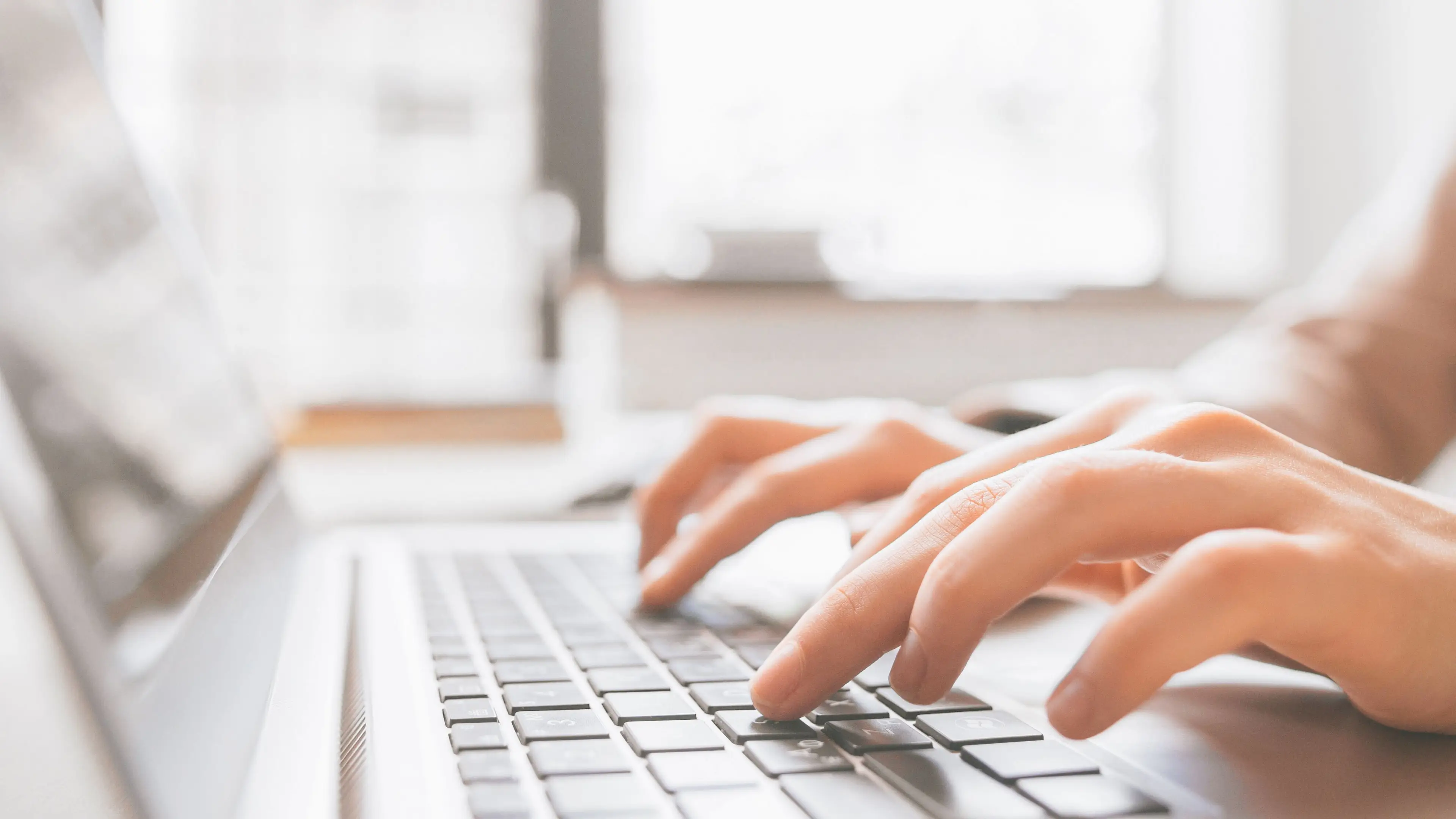 Hands typing on a laptop